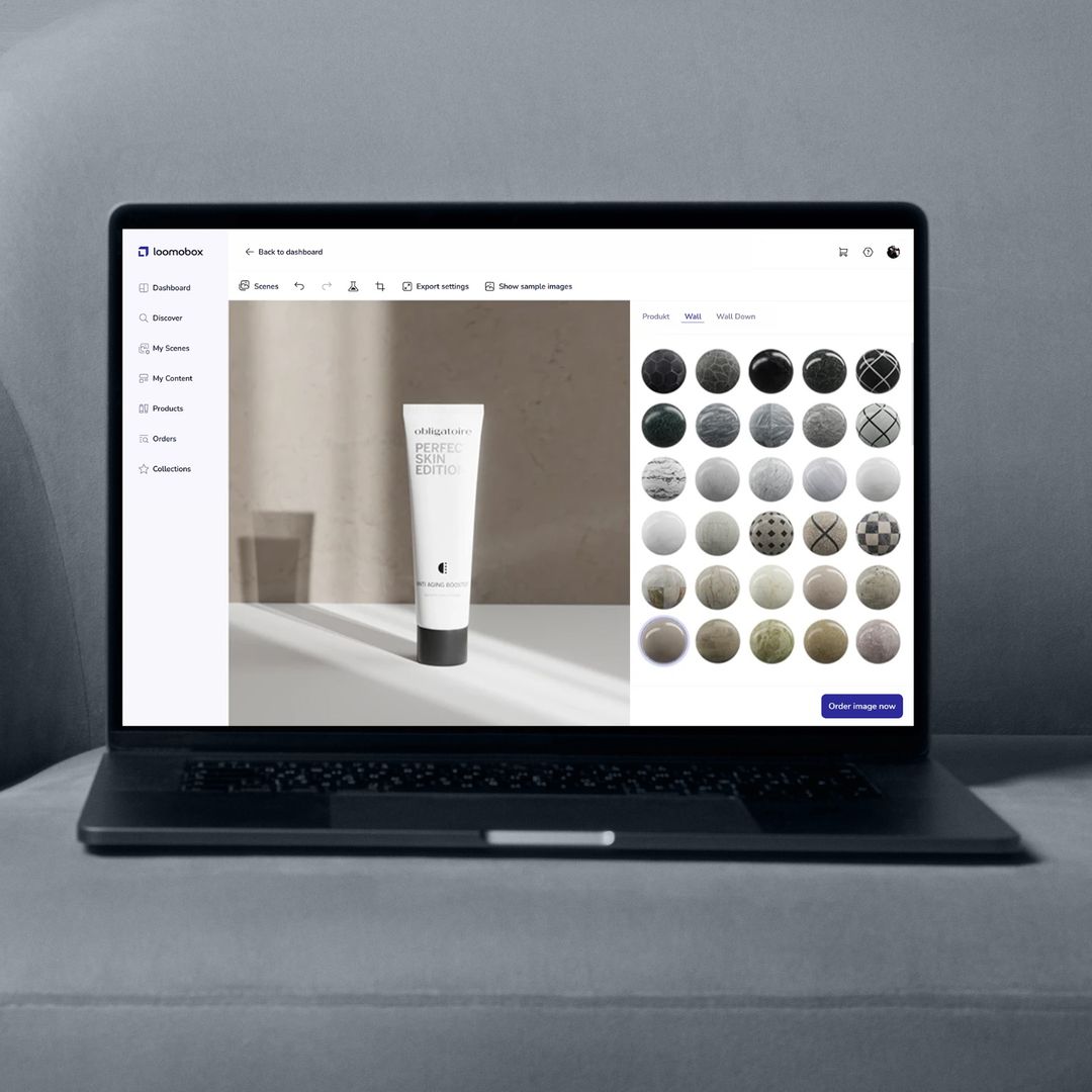 Laptop on a grey sofa showing the loomobox Content Studio with a skincare tube scene and material picker for backgrounds