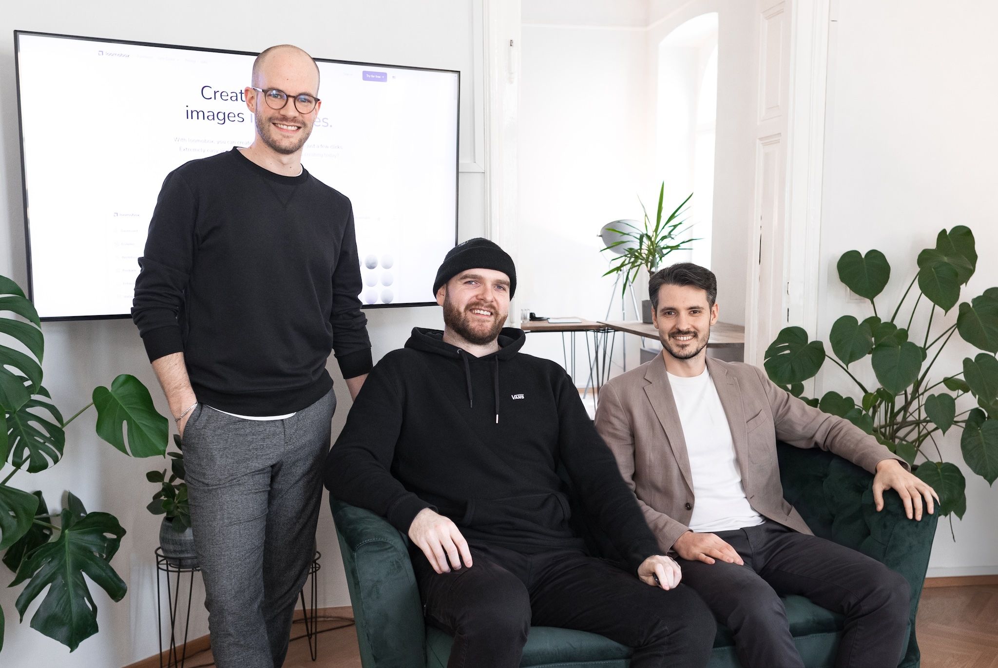 The three loomobox founders in their office, with the loomobox platform on a screen behind them