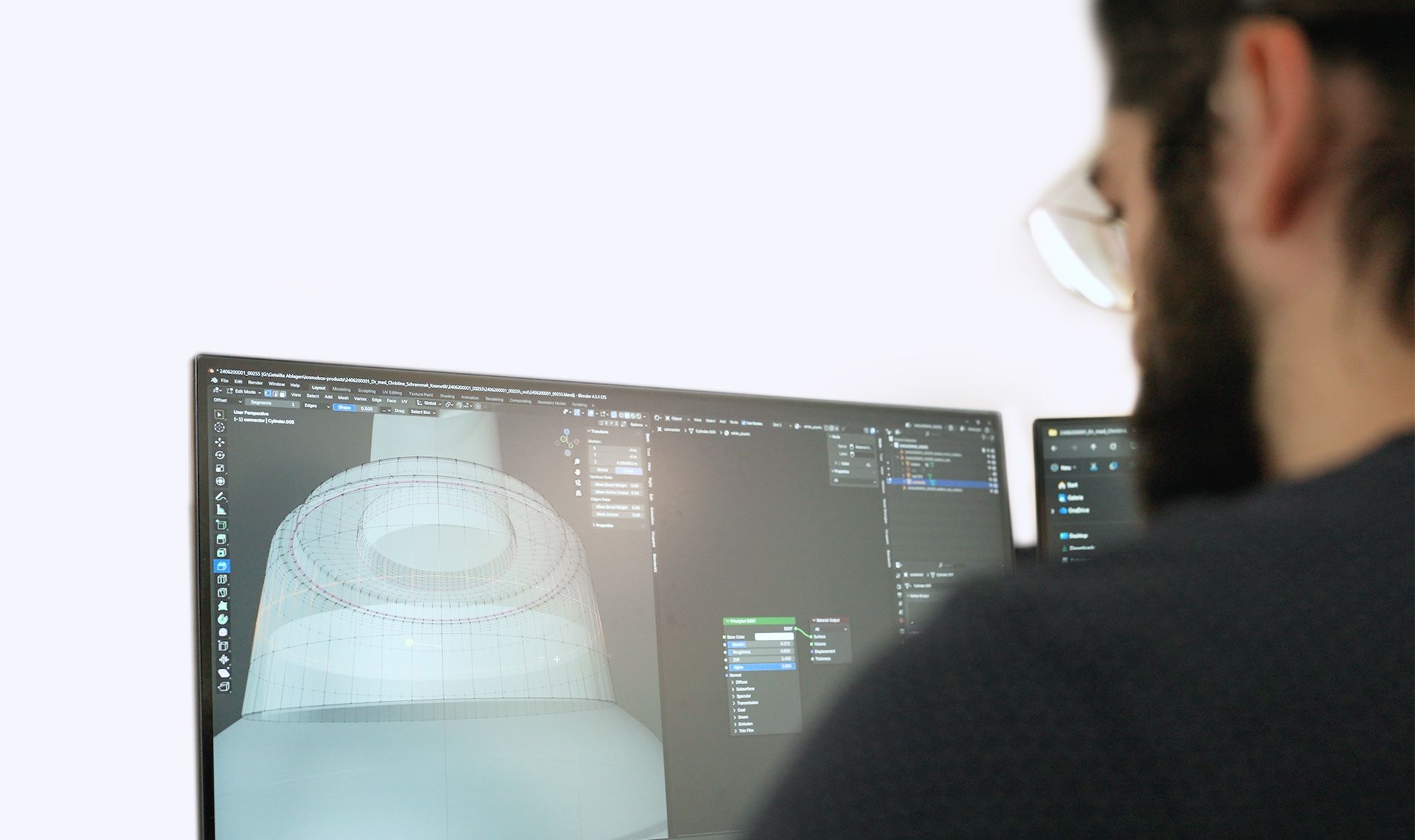 3D artist modeling the wireframe of a cosmetic jar on a monitor while building a loomobox digital twin