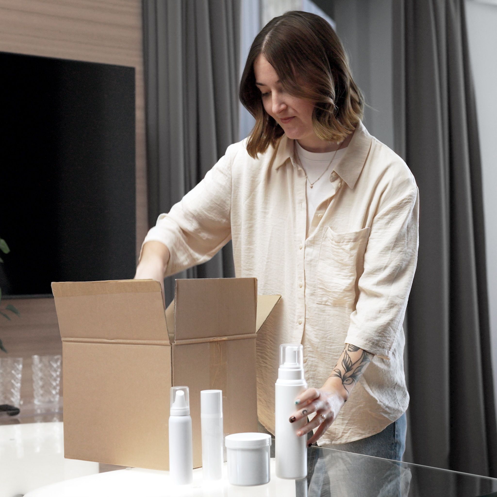 Woman packing cosmetic bottles into a shipping box to send products to loomobox for digital twin creation