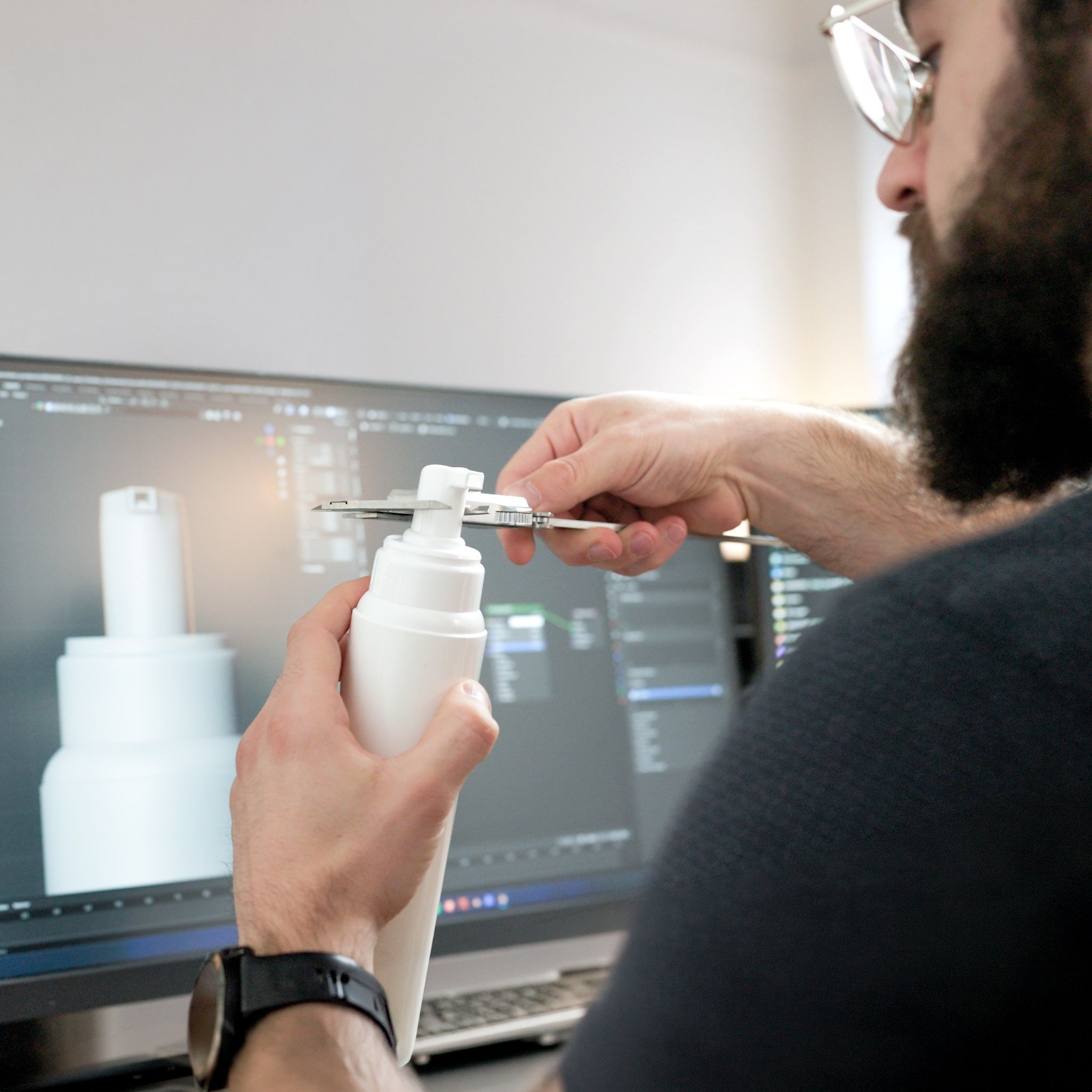 loomobox 3D artist measuring a cosmetic bottle with calipers while modeling its digital twin on screen