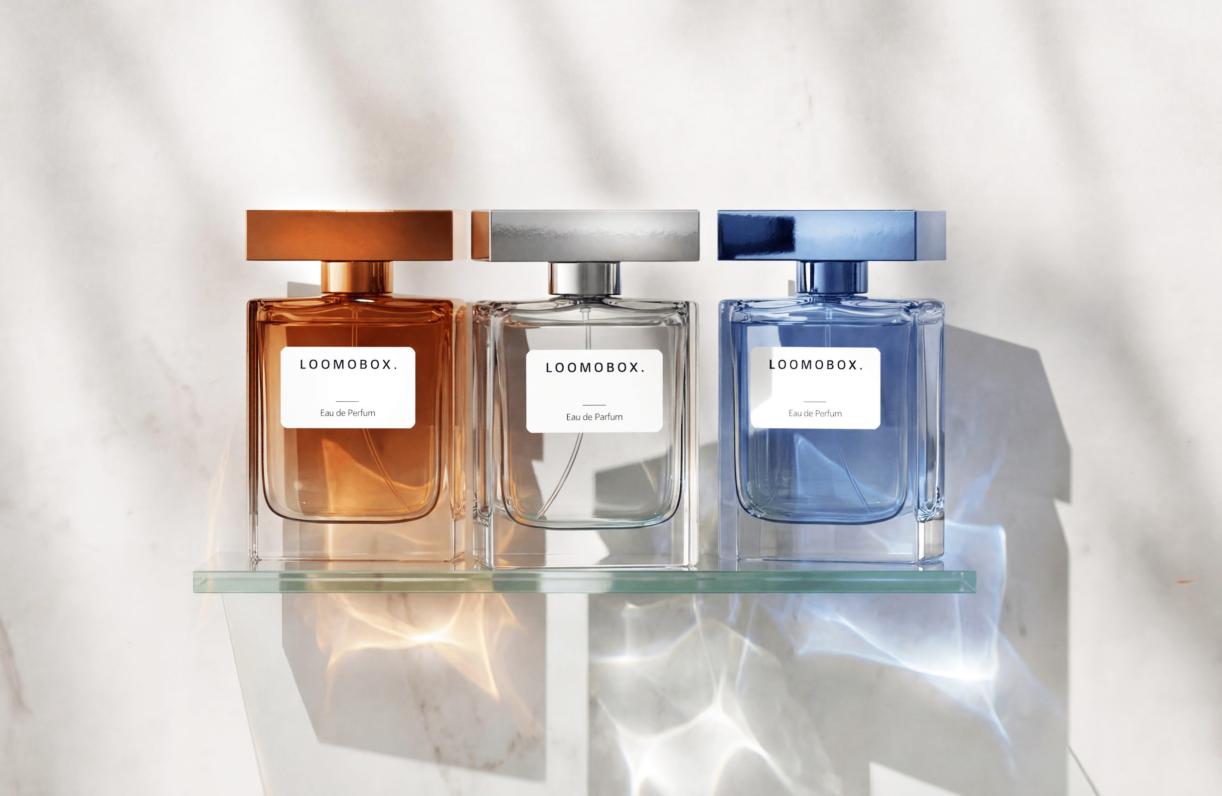 Three loomobox eau de parfum flacons in amber, silver and blue on a glass shelf with light reflections — 3D render created with loomobox