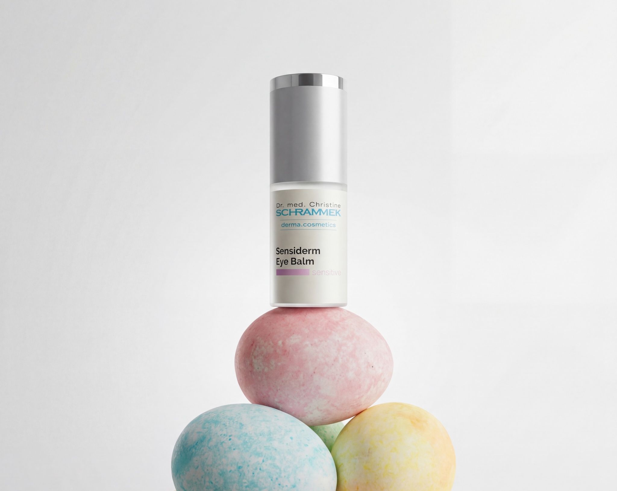 Dr. Schrammek Sensiderm Eye Balm balancing on a stack of pastel Easter eggs