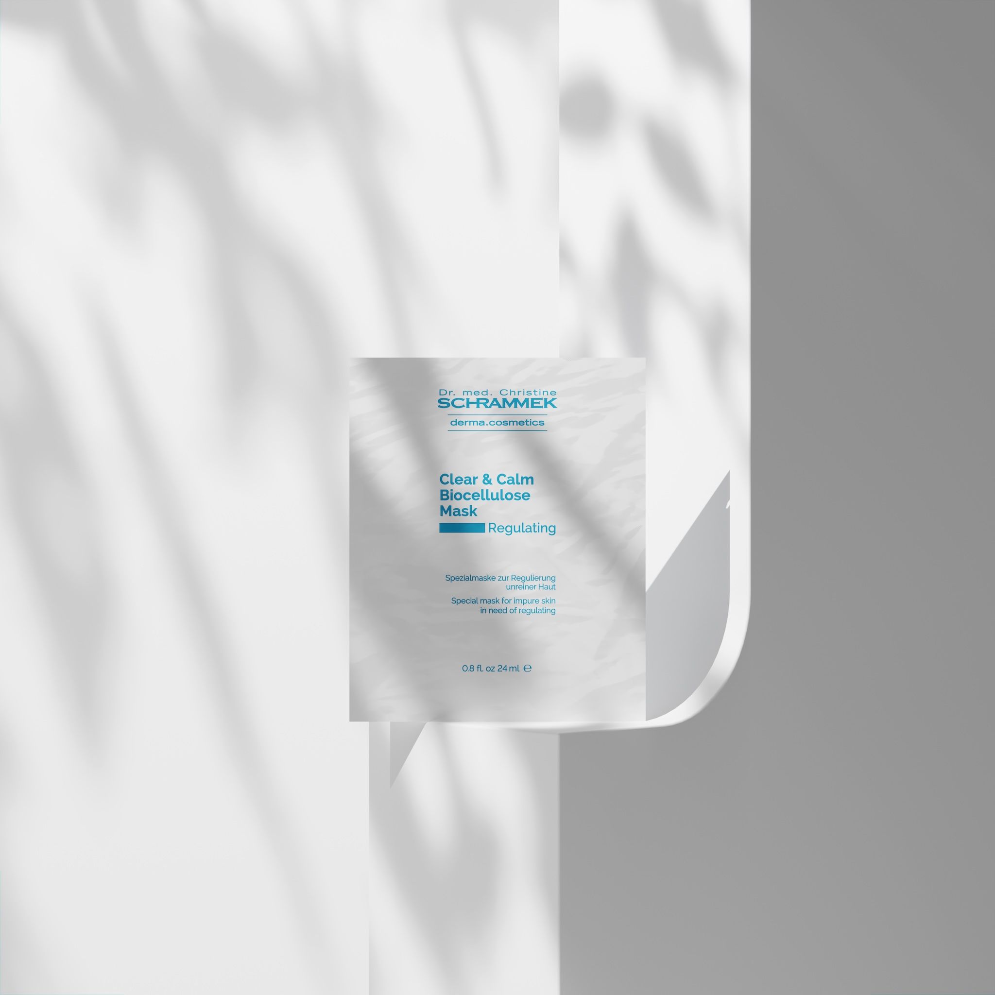 Dr. Schrammek Clear & Calm Biocellulose Mask sachet against white surfaces with leaf shadows