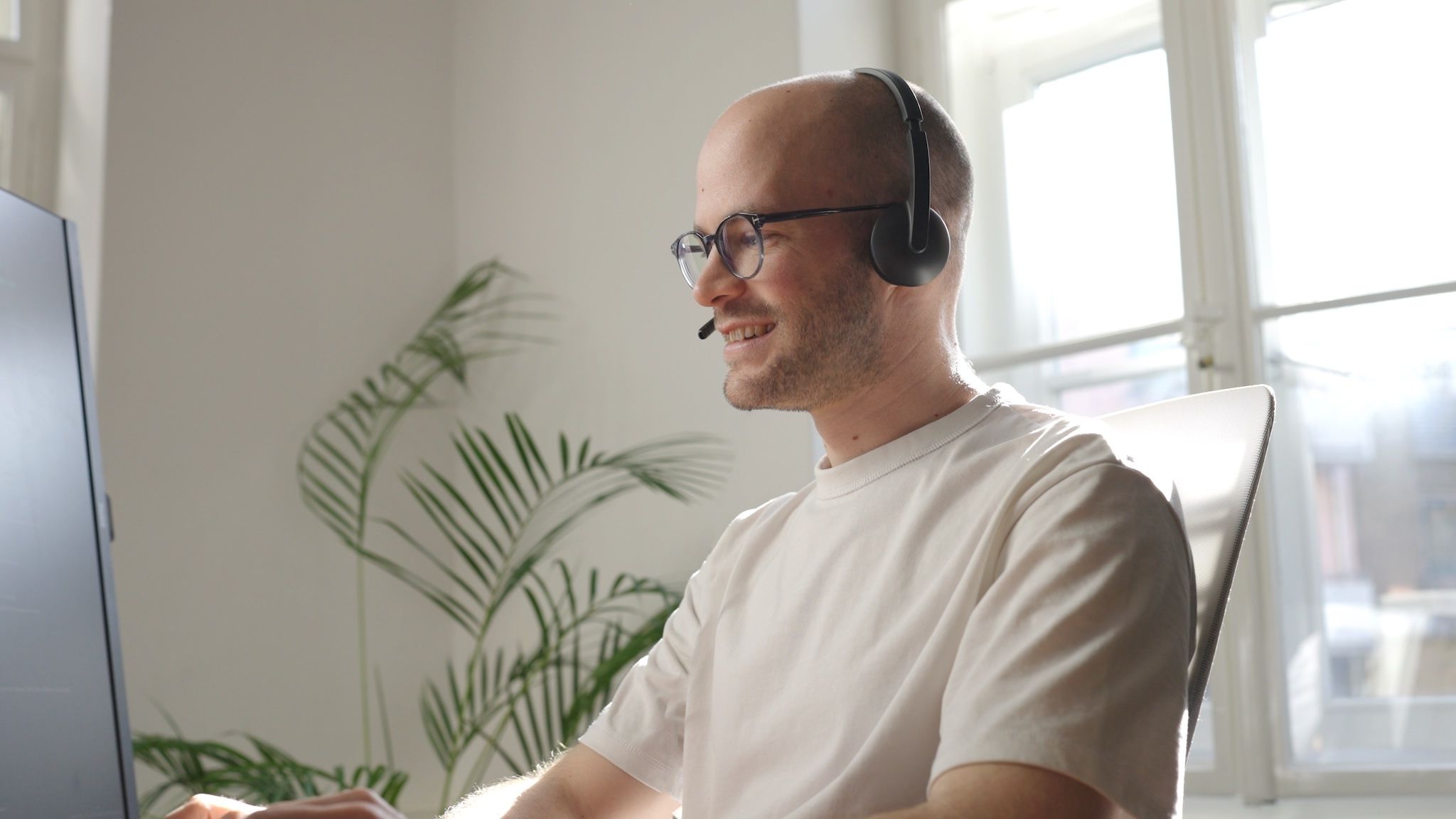 Michael from the loomobox team smiling during a video call, wearing a headset at his desk