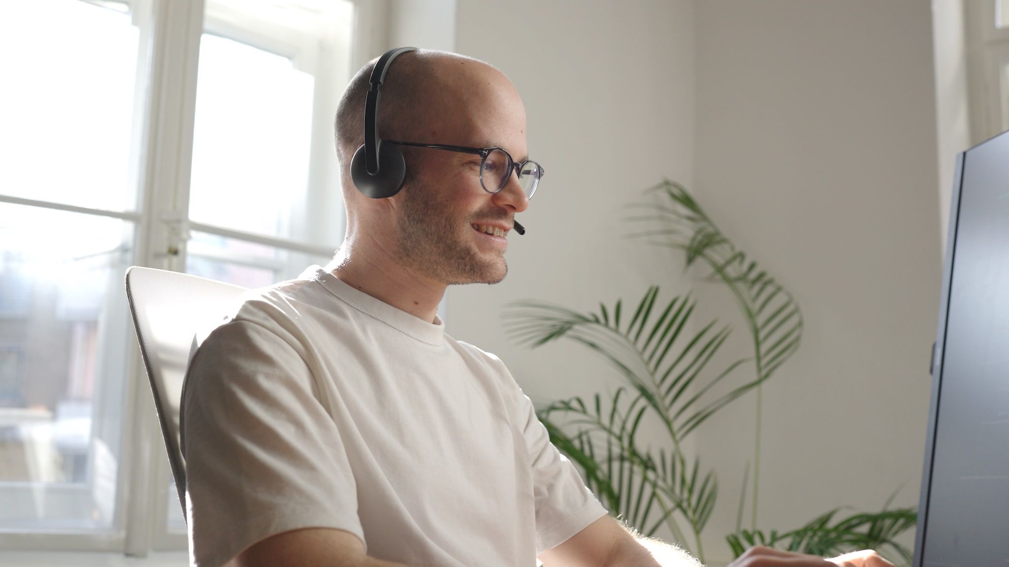 Michael from the loomobox team with a headset at his monitor, talking in a friendly support call