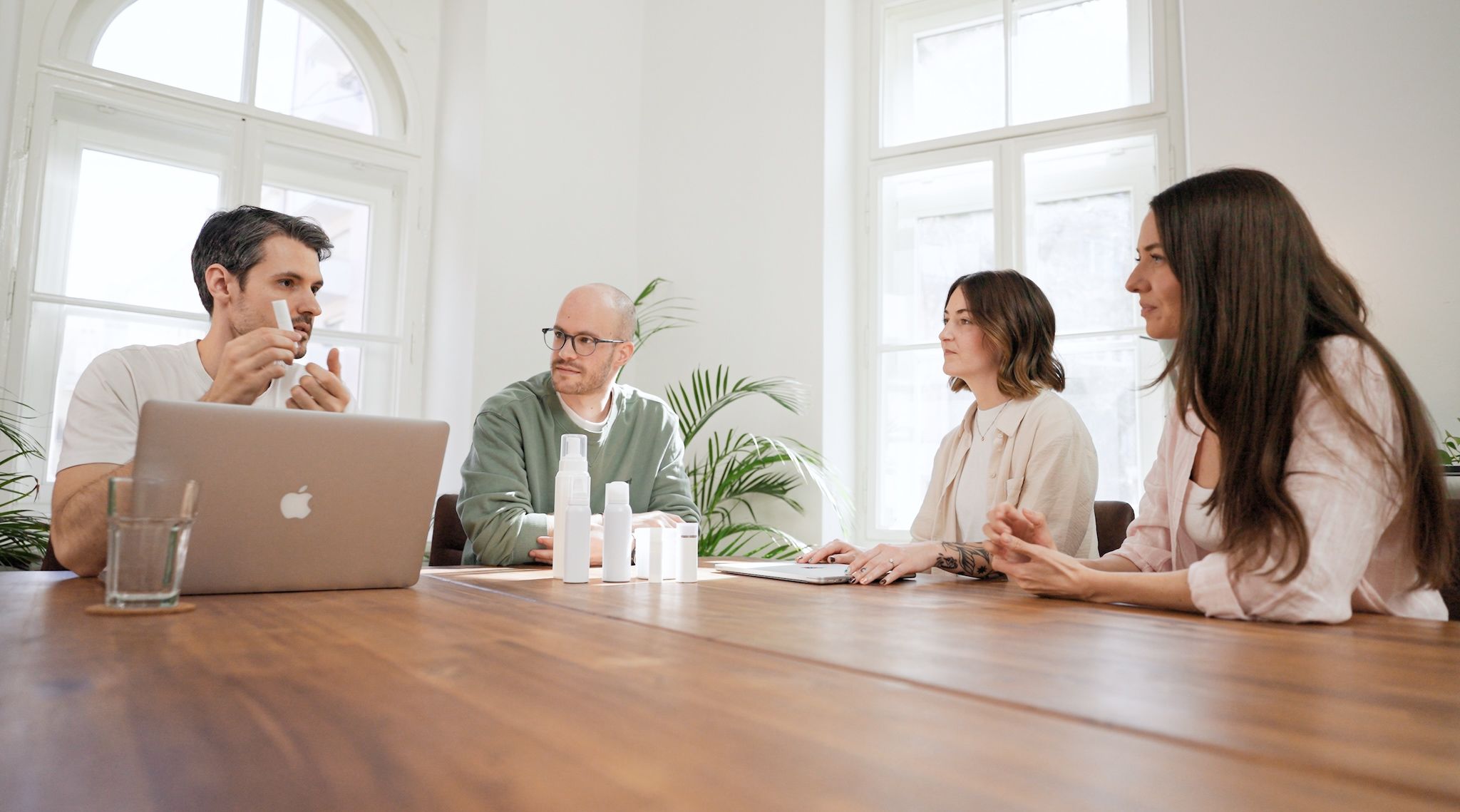 Four loomobox team members discussing skincare product packaging at a wooden table with a laptop