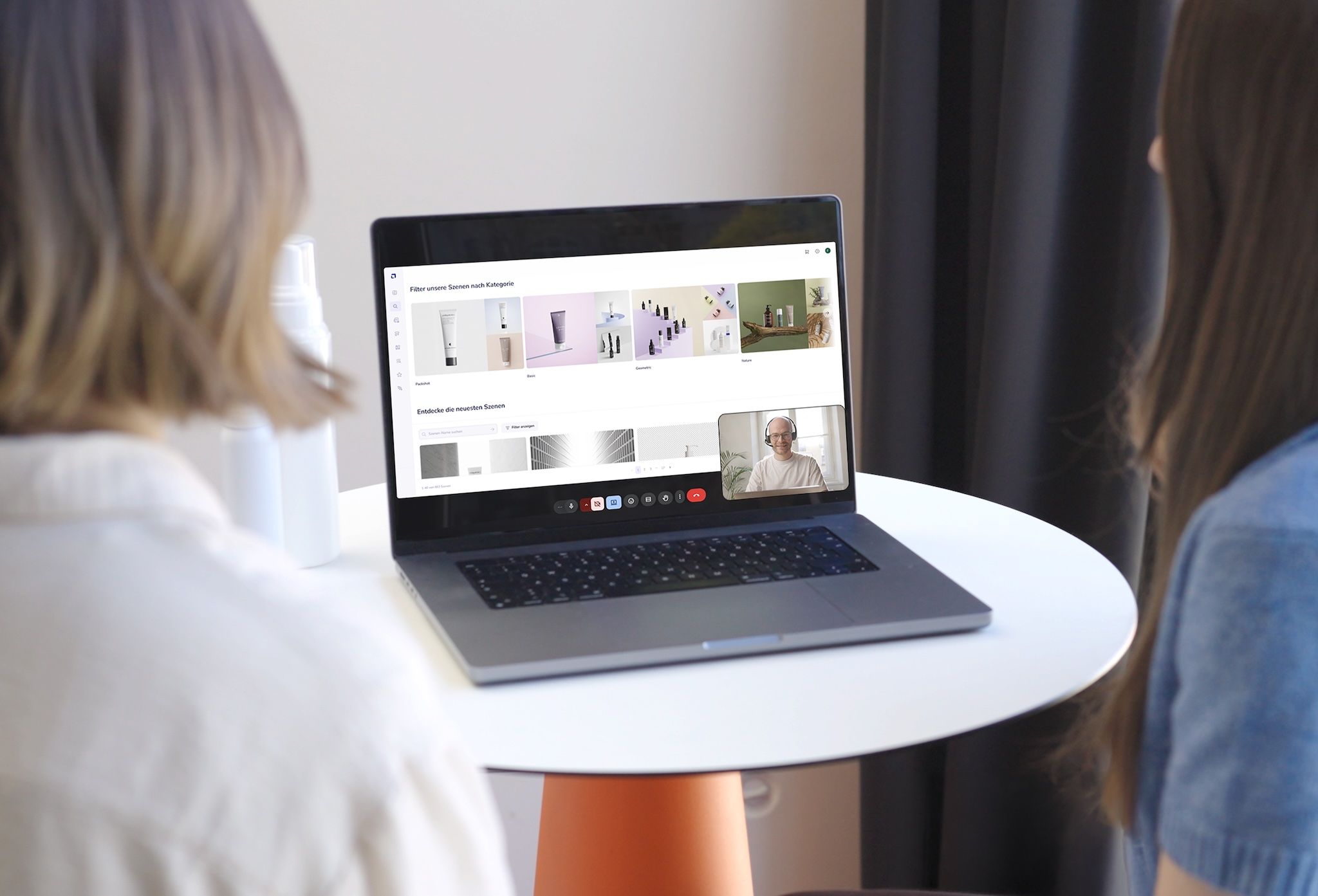Two customers on a video call with loomobox support, browsing the platform's scene library on a laptop